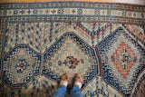 Vintage Caucasian carpet's geometric medallion featuring striped chevron lines and earthen tones.
