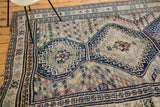 Geometric navy blue medallion and striped chevron banding on a vintage Caucasian carpet.