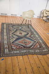 Geometric medallion and striped diamond chevron lines on vintage Caucasian carpet, navy, tangerine.