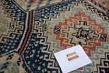 Vintage Caucasian rug's stepped geometric medallion with navy, tangerine, and seafoam colors.