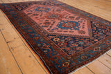 Vintage Malayer rug's intricate geometric medallion with cobalt blue and brick red on blush rose.