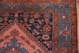 Vintage Malayer rug corner with blush rose, navy, and cobalt geometric patterns.