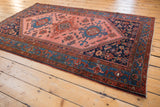Geometric brick red and cobalt blue Malayer borders, with navy corner and natural fringe.