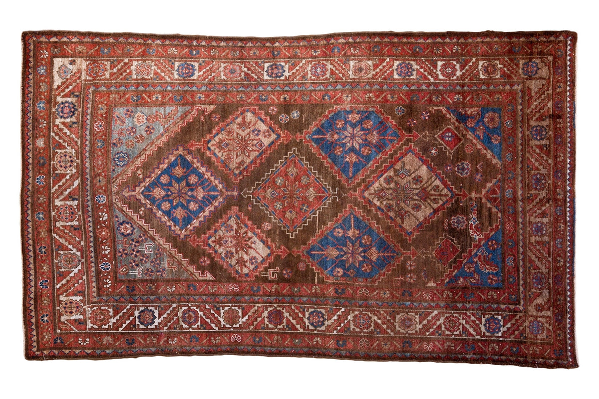 Vintage Persian Malayer rug: brown all-over diamond field, blue starbursts, and red borders.