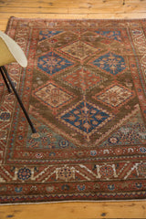 Malayer rug's chocolate brown field with cobalt blue diamond motifs and serrated leaf border.