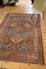 Vintage Malayer rug corner, showing brick red serrated leaf border and geometric floral bouquets.
