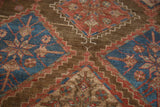 Textured close-up of vintage Malayer rug, showing cobalt blue, brick red, and brown geometric motifs.