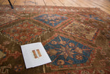 Hand-knotted Malayer rug detail: chocolate field with blue, red diamond panels and floral starbursts.
