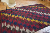 Dynamic diagonal zig-zag pattern on vintage Kilim rug in mustard, indigo, wine, and taupe.