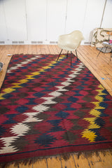 Vintage Kilim carpet with dynamic zig-zag pattern in red, indigo, yellow, taupe, and visible fringe.