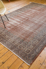 Distressed Oushak carpet corner displaying faded blush, auburn, and slate blue border motifs.