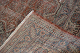 Distressed Oushak carpet corner, revealing fine hand-knotted weave in blush and slate blue.