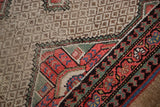 Distressed Hamadan rug detail: camel hair geometric field and a vibrant traditional border.