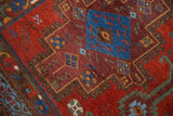 Antique Persian Afshar rug close-up; sapphire blue field with symbolic fish motifs on ruby ground.