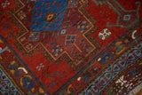 Hand-knotted antique Afshar rug's fringed edge, ruby red field, and symbolic blue fish motifs.