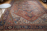 Vintage distressed Heriz carpet showing geometric brick red and blue patterns.