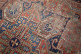 Vintage Heriz carpet, showcasing geometric brick red and blue patterns with time-softened pile.