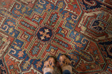 Distressed Persian Heriz carpet with geometric pattern, serrated leaves in brick red and blue.