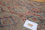 Vintage Jijim carpet texture showing rectilinear faded red, blue, and ivory patterns.
