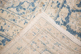 Vintage Tabriz carpet corner with hand-knotted back, fringed edge, and worn blue and beige pile.