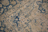 Patinaed blue palmette and curvilinear designs on a sand-beige field of a vintage Tabriz carpet.