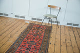 Soft raspberry red field of the Lilihan runner with repeating floral bouquets in slate blue.