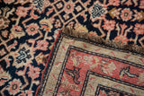 Antique Karabagh runner corner: hand-knotted coral and navy Herati pile, visible woven foundation.