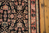 Karabagh runner's bold coral border contrasting with charcoal field Herati motifs.