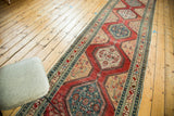 Segment of antique North West Persian runner, showing cherry red, teal medallions, and patterned borders.