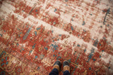 Antique Heriz rug showcasing heavy wear, exposed foundation, rust, cream, blue patterns.