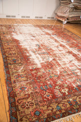 Heavily distressed field contrasting with the Heriz carpet's patterned red, blue border.