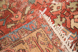 Distressed Antique Heriz rug corner, showing exposed hand knotted foundation and low pile.