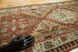 Angled view of the vintage Serab rug's geometric latch motif in brick red and coffee brown.