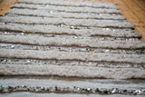 Alternating plain weave, thick piled bands, and shimmering silver sequins.