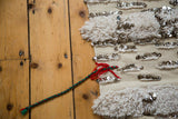 Handira detail featuring alternating ivory pile, plain weave, silver sequins, and red green tie.