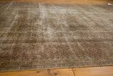 Distressed vintage Sivas carpet showing textured pile and muted floral vine pattern in wooded tones.