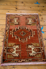 Hand-knotted vintage Oushak rug corner: rust red field, ivory serrated geometric patterns, fringed edge.