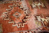 Close-up of vintage Oushak rug pile revealing abrashed rust field and ivory geometric motifs.
