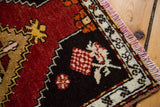 Vintage Oushak rug corner: checkered lily motif, black field, ivory border, pink fringe.
