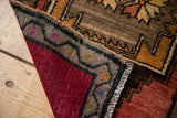 Hand-knotted Oushak rug folded, revealing madder root red foundation and colorful patterned edge.