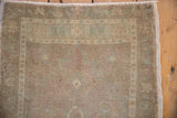 Textured vintage Oushak rug pile with geometric border in beige, celadon, and pale mauve.