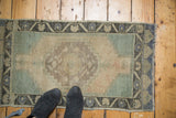 Vintage Oushak rug detail: meandering leaf border, stepped spandrels, pale green, and beige.
