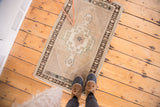 Fringed end of vintage Oushak rug with visible charcoal brown geometric border.
