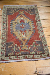 Lower left corner of hand-knotted Oushak rug, charcoal, red, mint green geometric border.