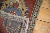 Folded hand-knotted Oushak rug showing geometric patterns in cherry red and slate blue.