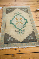 Corner detail of the vintage Oushak rug, showing teal green and charcoal brown geometric spandrel motifs.