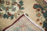 Vintage Oushak rug mat corner, beige pile with teal, purple motifs, and woven foundation.