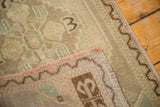 Oushak rug corner revealing hand-knotted back, pink side binding, fringe, and zig-zag border.