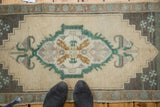 Emerald green quatrefoil, ram's horn pendants, and pinwheel motifs on a beige Oushak rug.