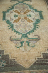 Oushak rug corner with beige and emerald green pinwheel and rams horn motifs.
